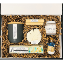 Load image into Gallery viewer, The deluxe self-care gift box is pictured. It contains a ceramic candle with a lid, a 4-pack of shower steamers / shower bombs, a bath bomb, a lavender sugar scrub, a wax melt, and color-tip matches.