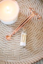 Load image into Gallery viewer, Rose gold wick trimmers are shown, along with white color-tip matches and a lit candle