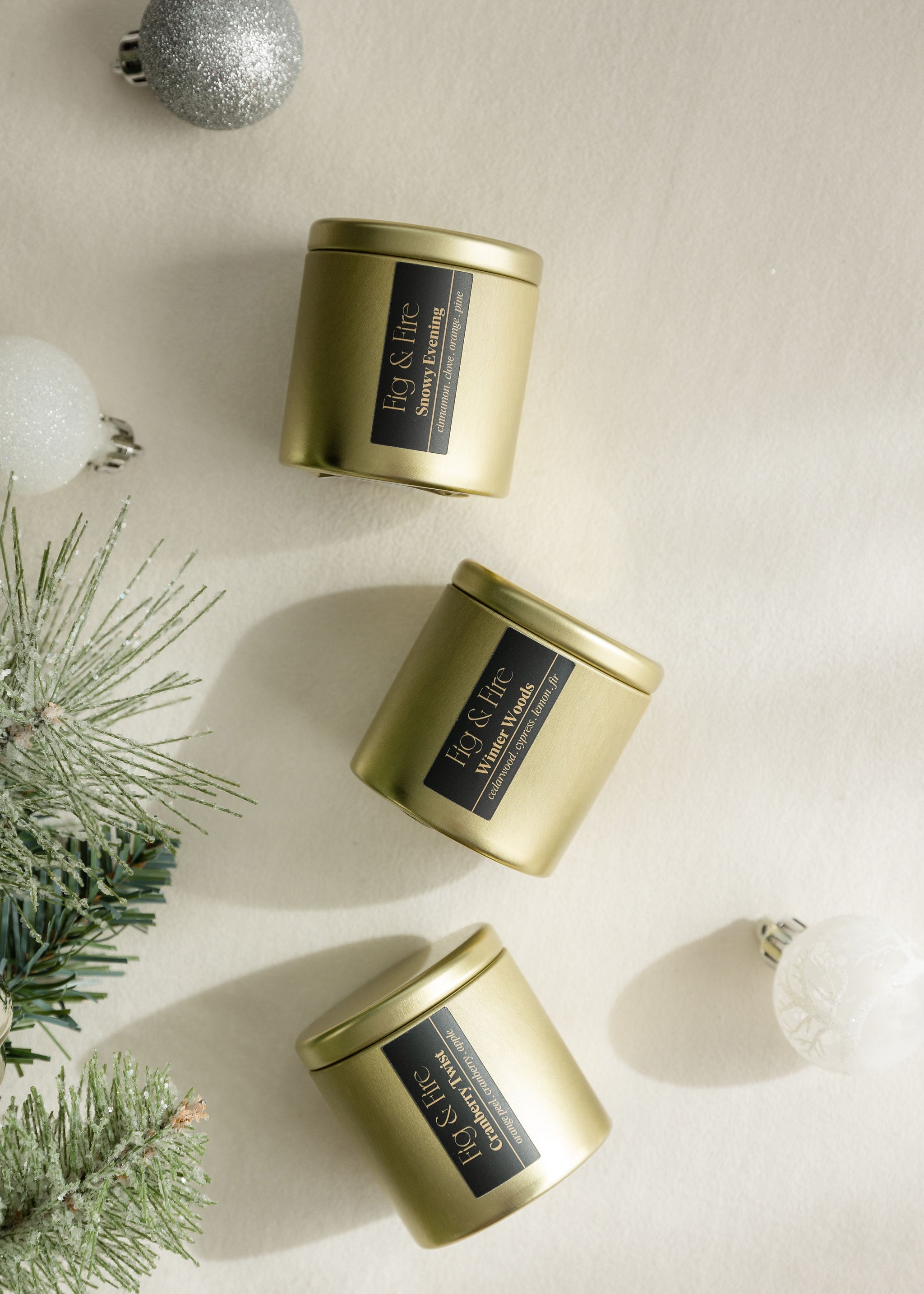 3 gold tin candles - The entire winter collection is featured, with a burn time of 24+ hours each: Cranberry Twist, Snowy Evening, and Winter Woods - non-toxic, all-natural, cruelty-free, vegan, soy candles made with essential oils