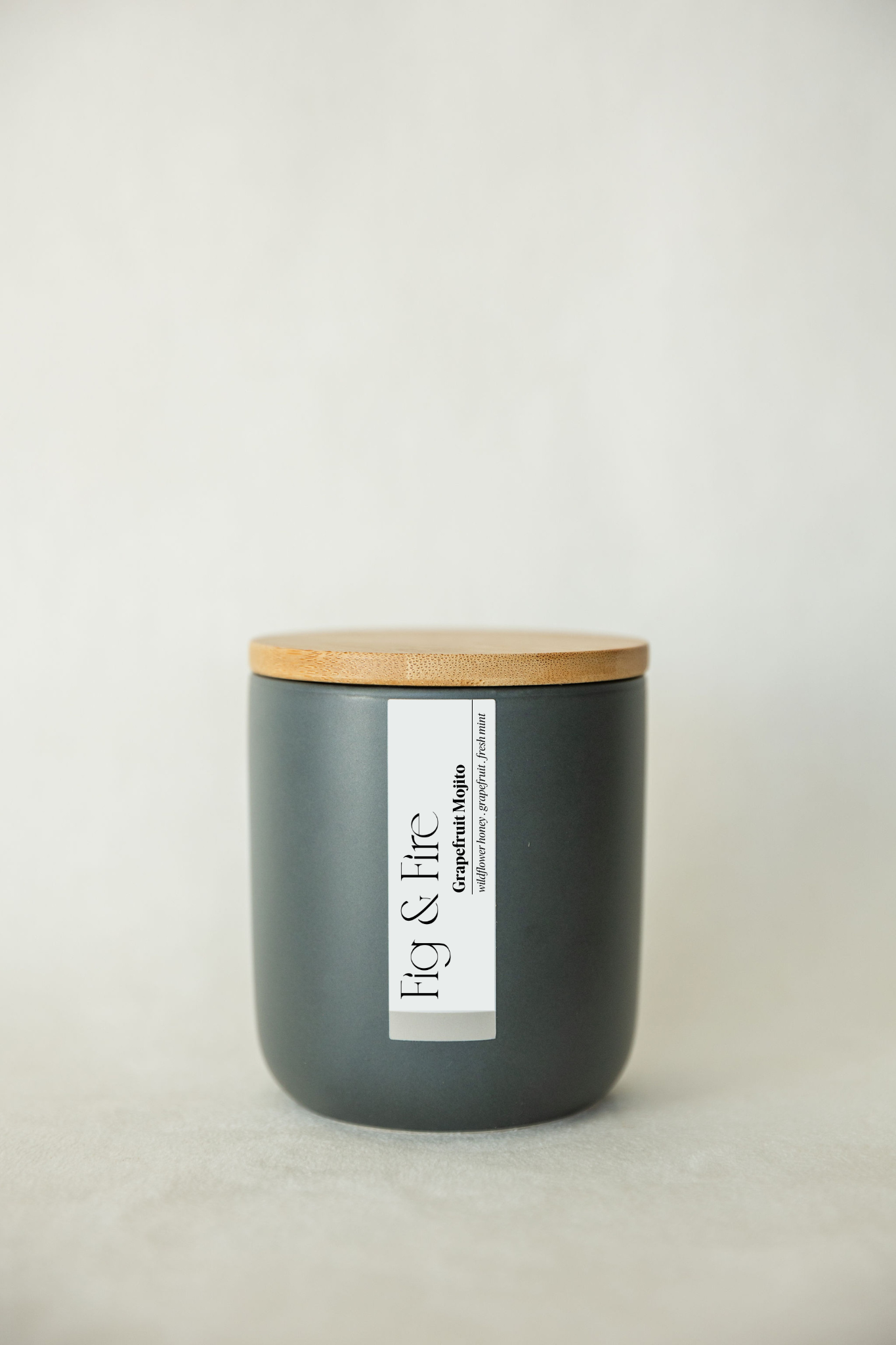 Handcrafted candle - scent is Grapefruit Mojito - scent notes are wildflower honey, pink grapefruit, and fresh mint - all natural soy candle - vegan, non-toxic, made with essential oils - container is a charcoal ceramic tumbler with a bamboo wooden lid