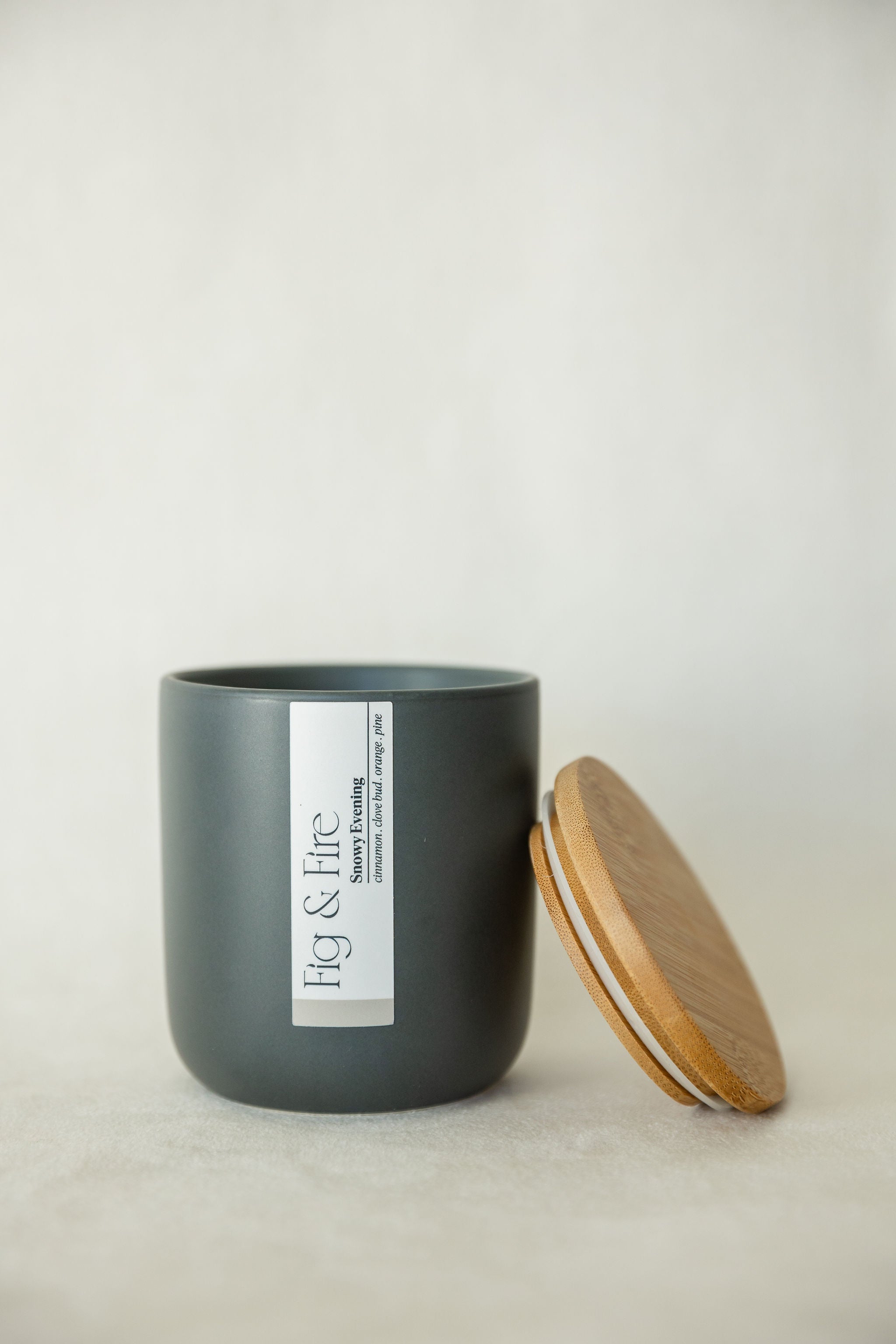 Handcrafted winter candle - scent is snowy evening - smells of clove, pine, orange, and cinnamon - all natural soy candle - vegan, non-toxic, made with essential oils - seasonal collection - container is a charcoal ceramic tumbler