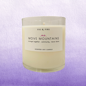 Image of the Move Mountains clear glass candle for The Breasties. Background image has different shades of lavender purple.