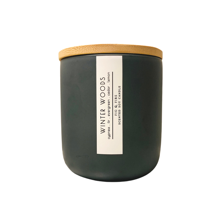 Handcrafted winter candle - scent is winter woods - smells of cypress, fir, evergreen, cedar, and lemon - all natural soy candle - vegan, non-toxic, made with essential oils - seasonal collection - container is a charcoal ceramic tumbler with a light brown bamboo wooden lid